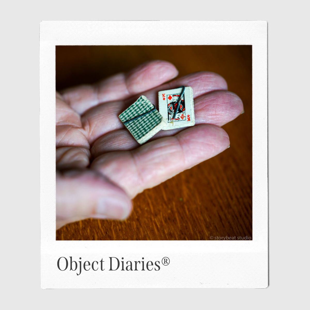 A Polaroid-style photo of Stan Weiss's hands holding two halves of a miniature deck of cards. Object Diaries appears in the white space below the photo.